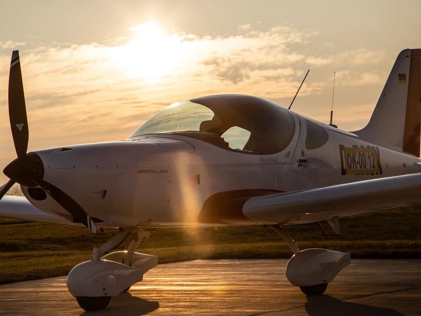 Un Bristell B23 blanc stationné sur le tarmac dans la lumière rasante du soir
