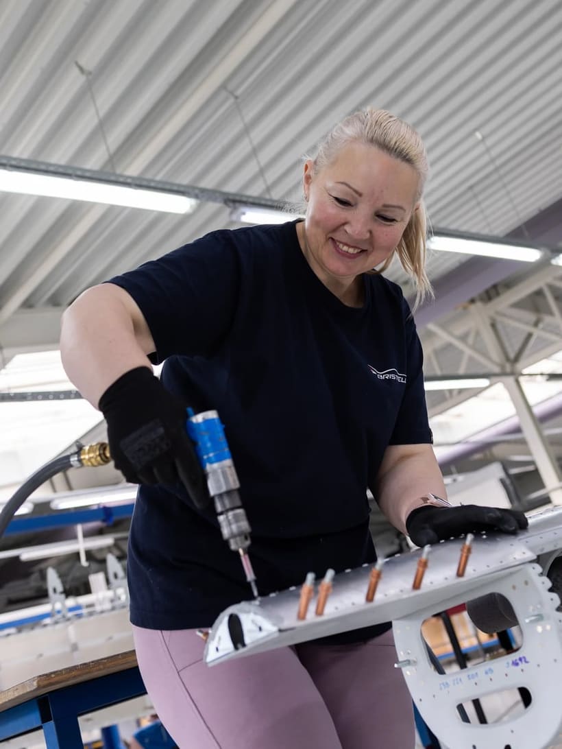 A Bristell technician using a pneumatic tool on an all-metal airframe sub-assembly held with clecos on the production line