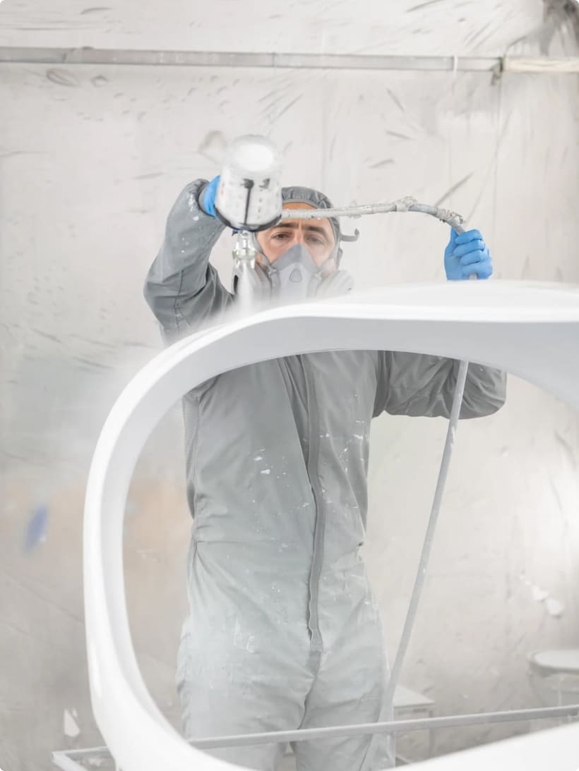 Bristell finisher spray-painting an aircraft canopy in the paint booth