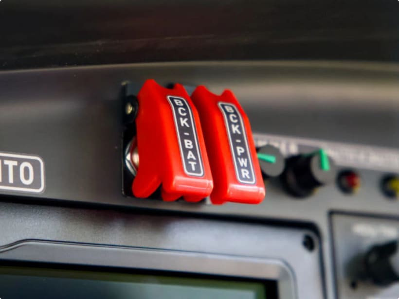 Cockpit panel switches with red safety guards for the backup electrical battery.