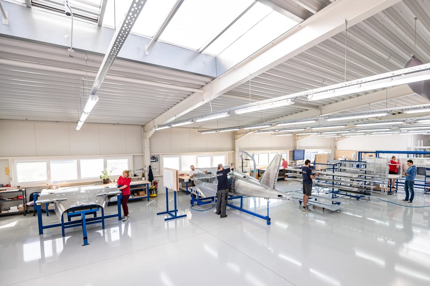 The BRM AERO production hall in Kunovice, with a technician working on a bare metal Bristell fuselage on stands